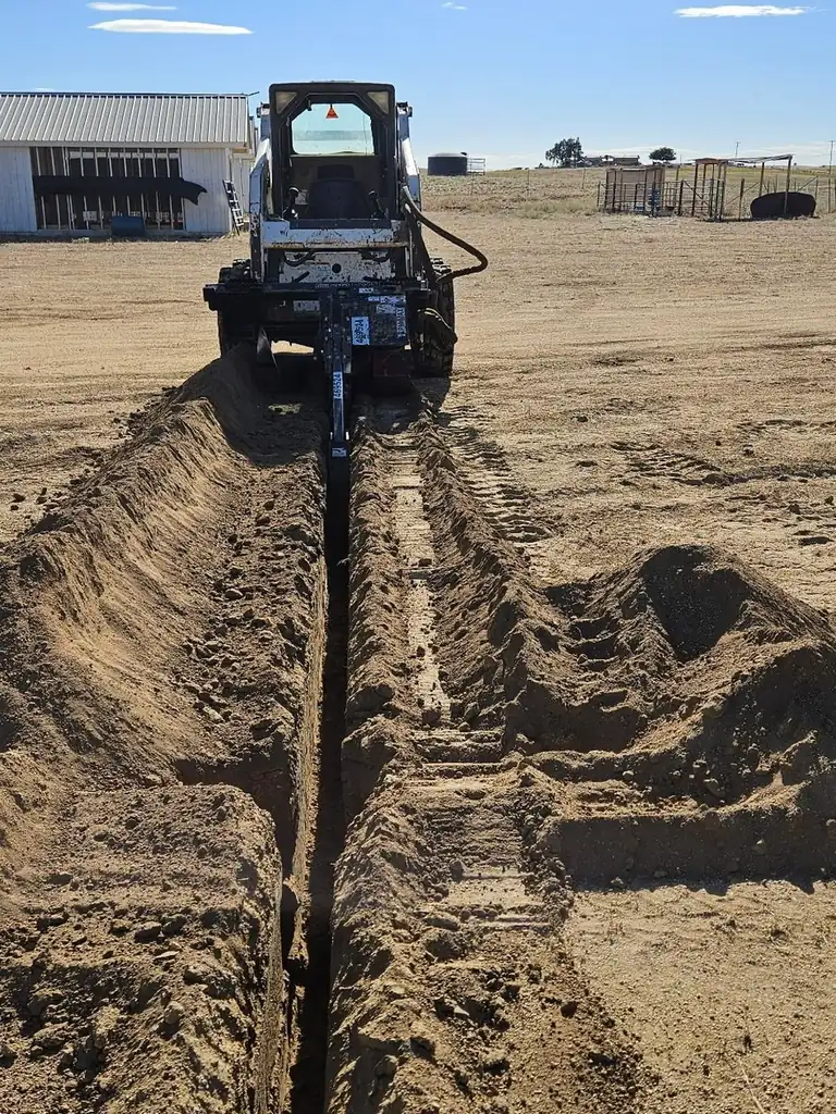 Superior Hauling Bobcat skid steer trenching and moving dirt on a Central Valley lot