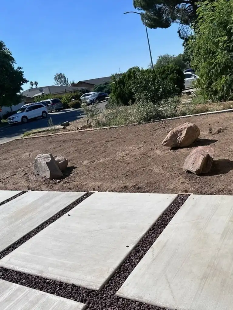 Delivered landscape boulders placed on graded ground beside a paver walkway in Madera, CA