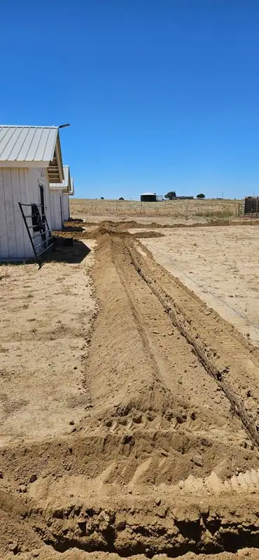 Graded trench line running alongside a metal building