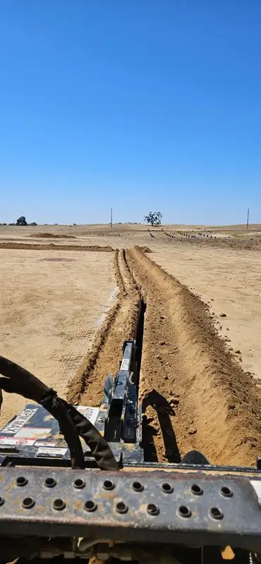 Trenching work in progress across a wide open field