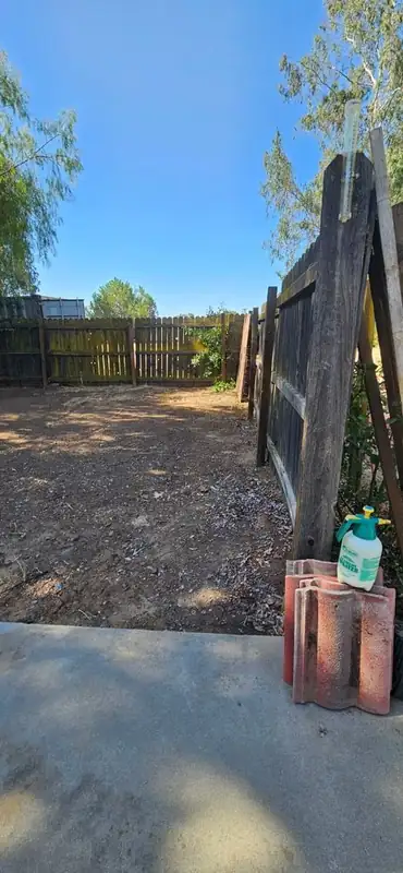Backyard cleared out behind a wood gate, hauled clean